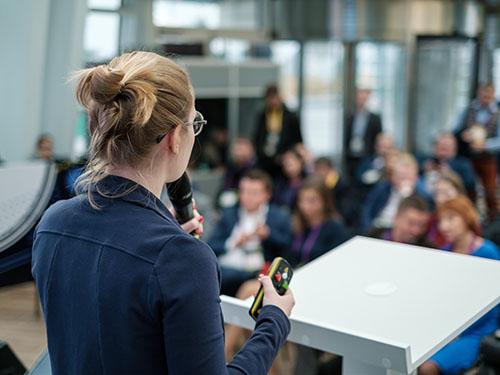 A woman addresses a crowd with a microphone