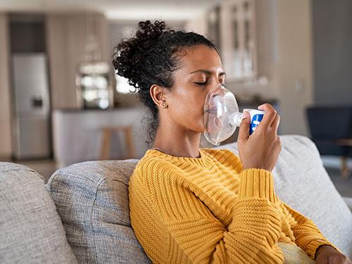 A woman holds a oxygen mask up to her face